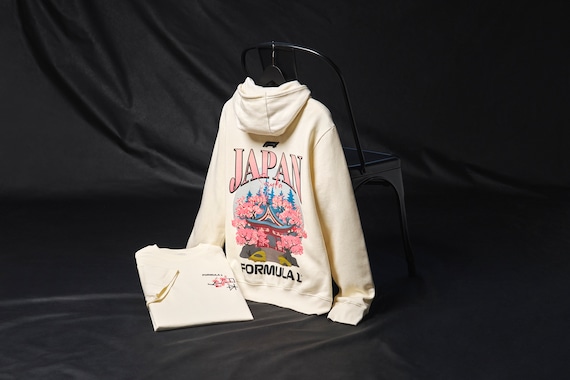 Mentre la Formula Uno si dirige in Giappone per il Gran Premio del Giappone 2025, preparati per l'evento principale con questo abbigliamento ufficiale che celebra la cultura e il design giapponese. Un ramo di ciliegio è raffigurato sul petto con scritte sia in inglese che in giapponese, mentre la parte posteriore presenta un'opera d'arte di un tradizionale tempio shintoista e la scritta Suzuka, sede di quello che sarà sicuramente un memorabile terzo round della stagione di F1 2025.